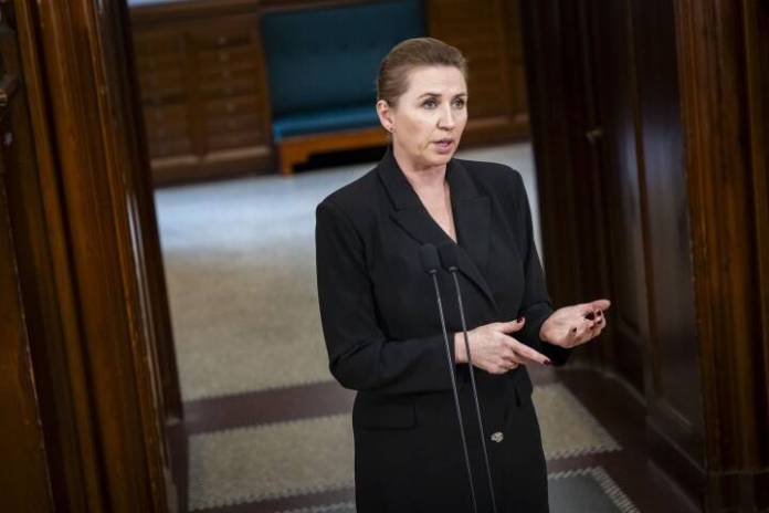 A person in a black suit standing in front of a microphone Description automatically generated